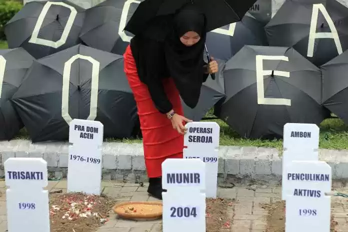 Mahasiswi menabur bunga di atas replika makam dengan nisan bertulis kasus-kasus pelanggaran Hak Asasi Manusia (HAM) Indonesia di Surabaya, Jawa Timur, Kamis (10/12).