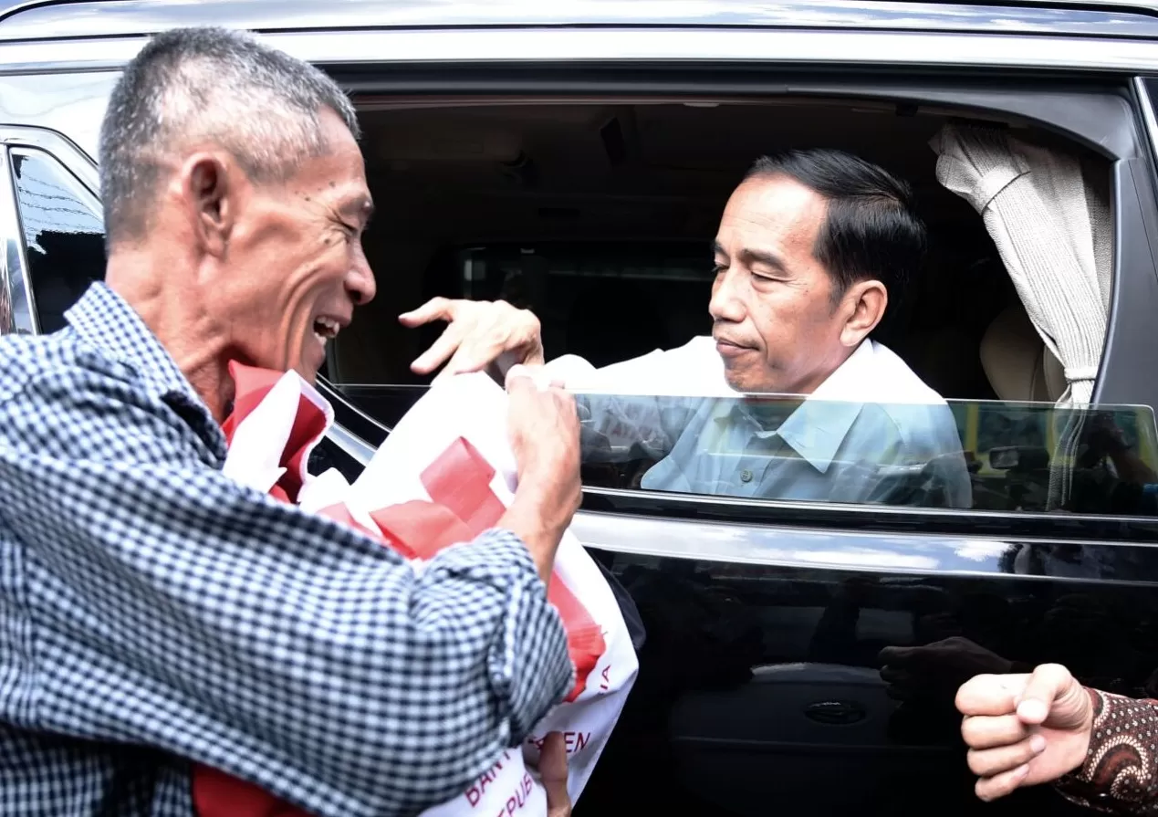 Presiden Joko Widodo saat membagikan sembako dari dalam mobil kepresidenan.